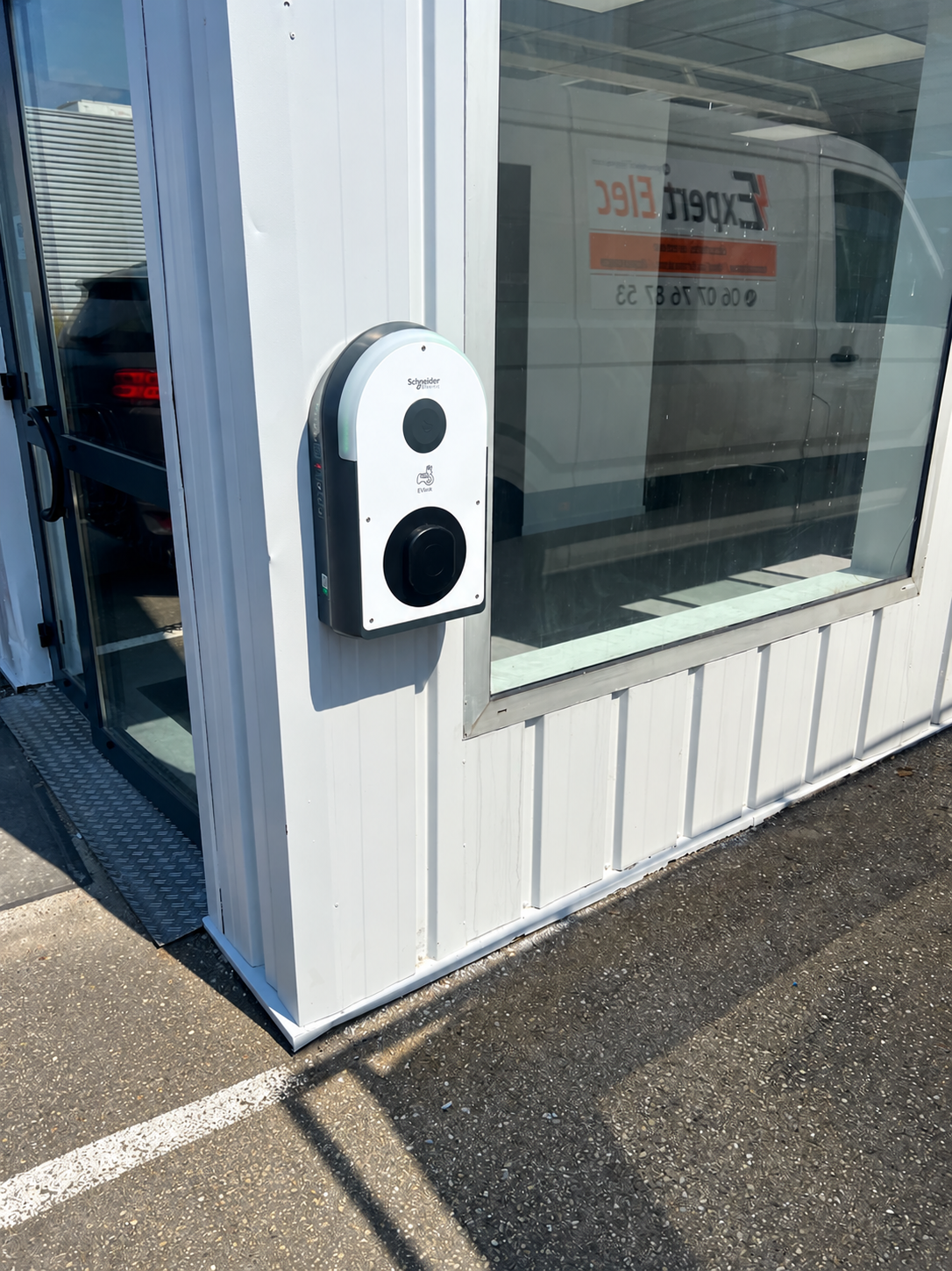 Borne de recharge pour véhicule électrique fixée sur la façade d’un bâtiment